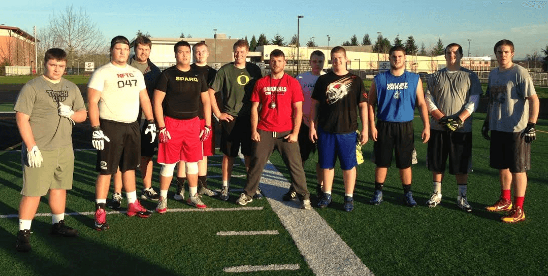 Barton Football Academy Line coach Alex Linnenkohl Center-Red) with the events lineman.