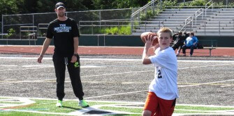 Elias Polanski prepares to throw on the run while coach Alex Brink looks on.